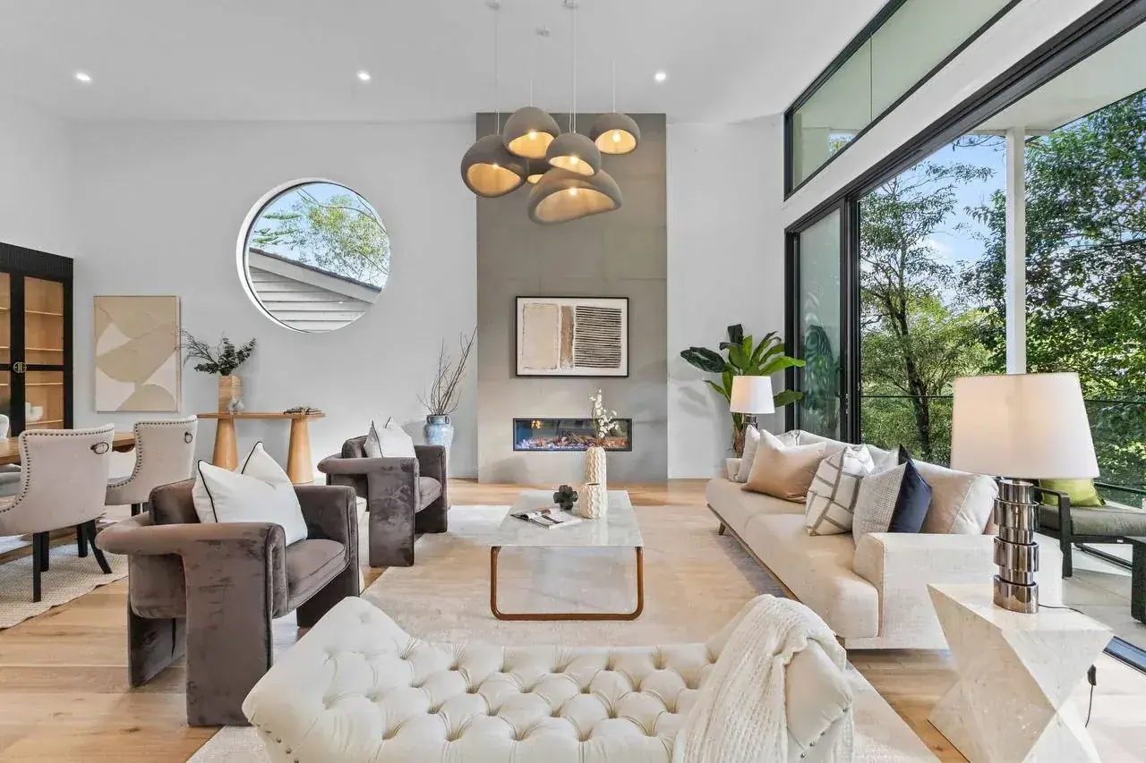 Living room with a large round window set into the wall beside a full-height fireplace